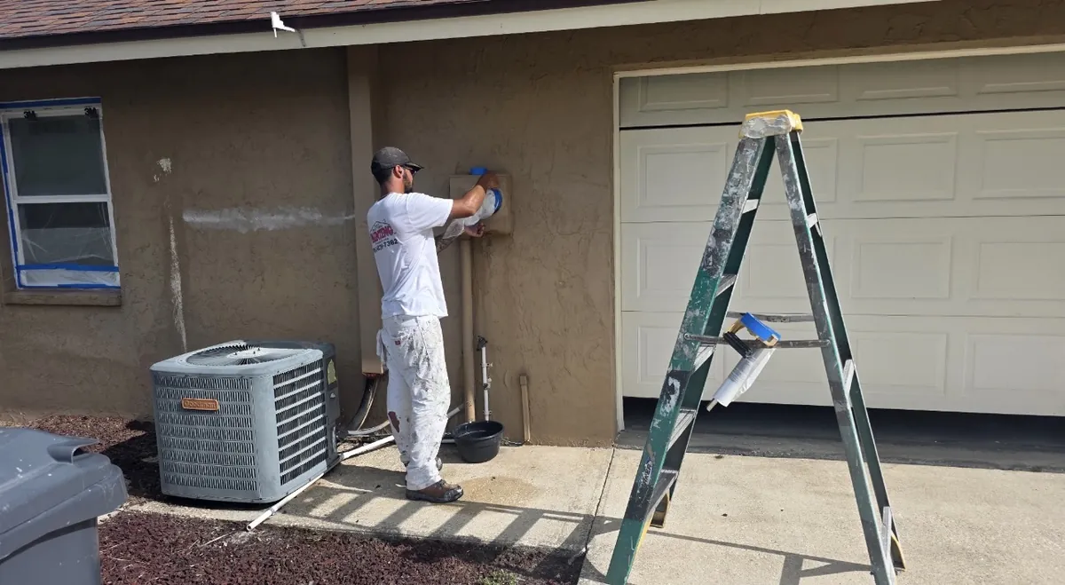 Professional painter preparing spray equipment during exterior house painting prep work in Lakeland Florida